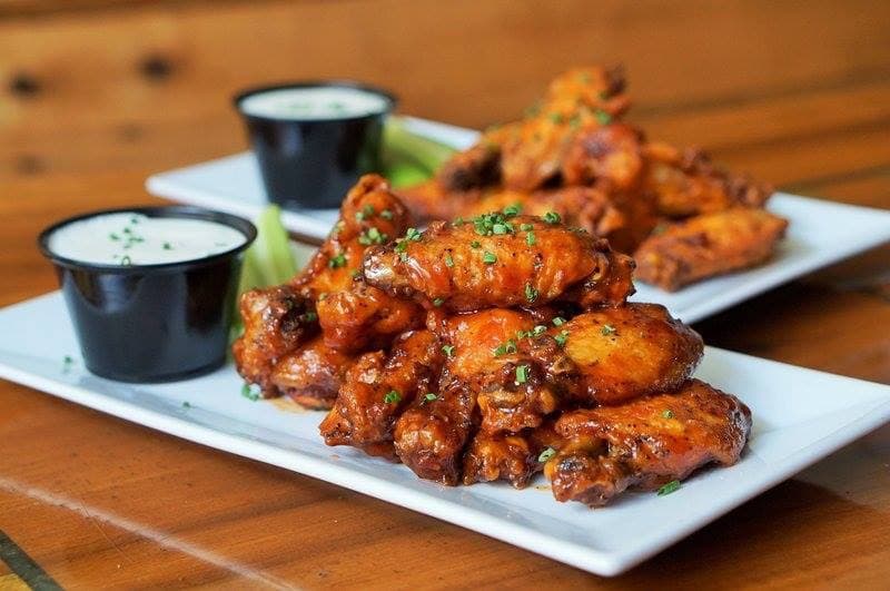 Glazed buffalo chicken wings topped with chives, served with ranch dressing and celery sticks.