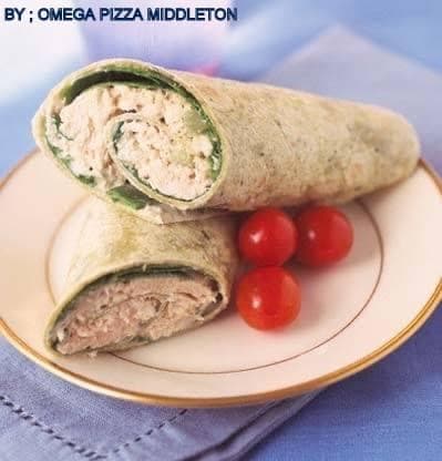 Halved spinach wrap filled with tuna salad and cherry tomatoes on a gold-rimmed plate.