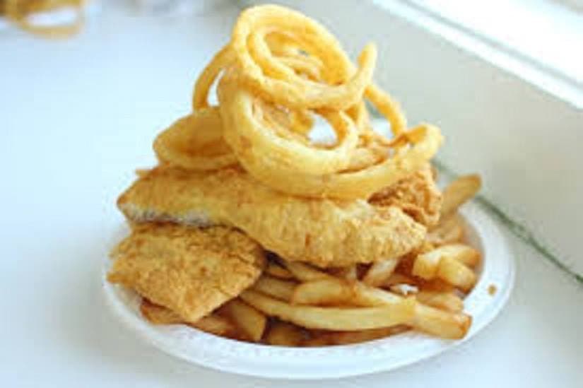 Golden-brown fried fish and French fries topped with a pile of crispy onion rings.