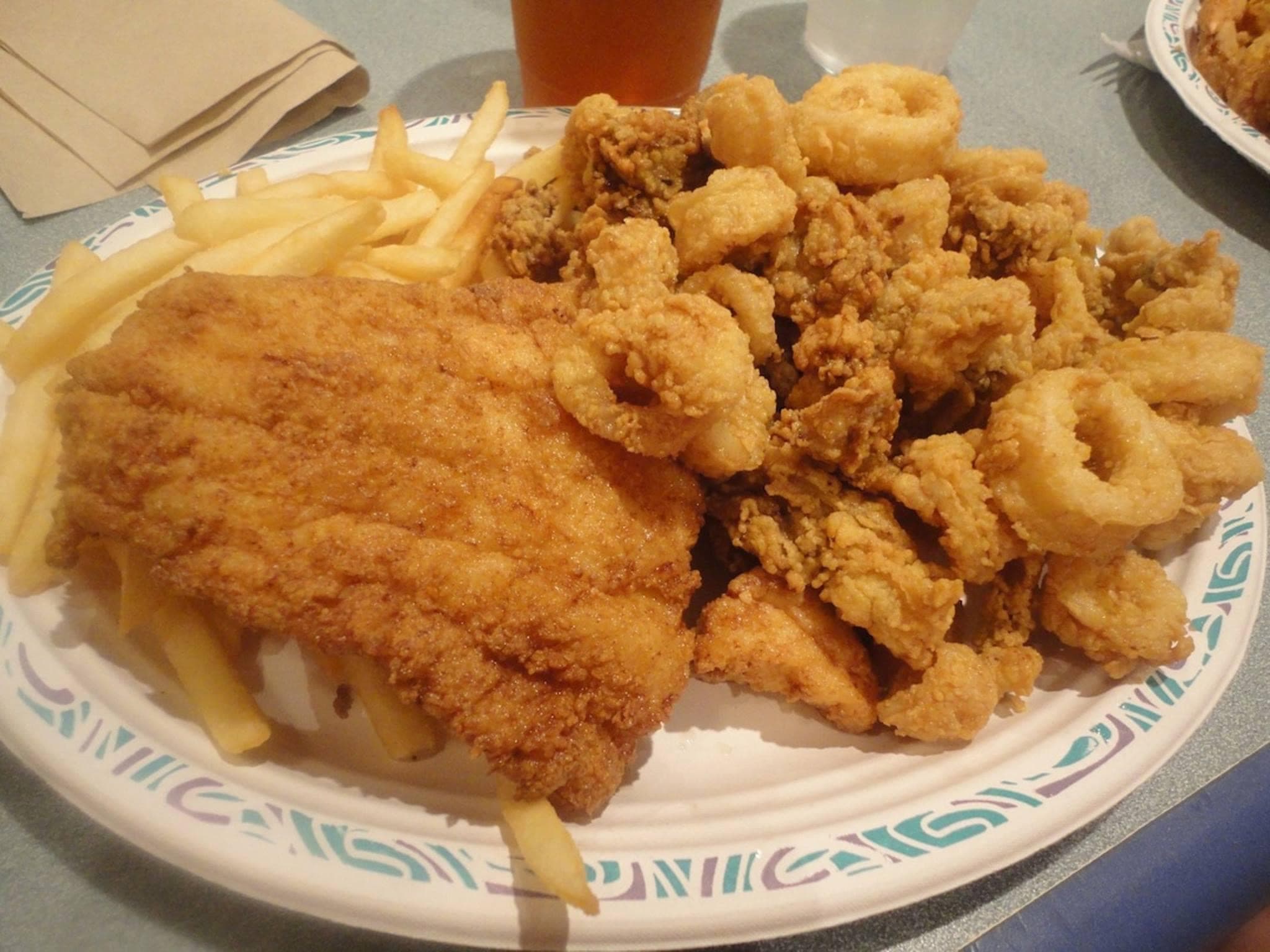 Golden fried fish fillet served with crispy calamari rings and a side of french fries.