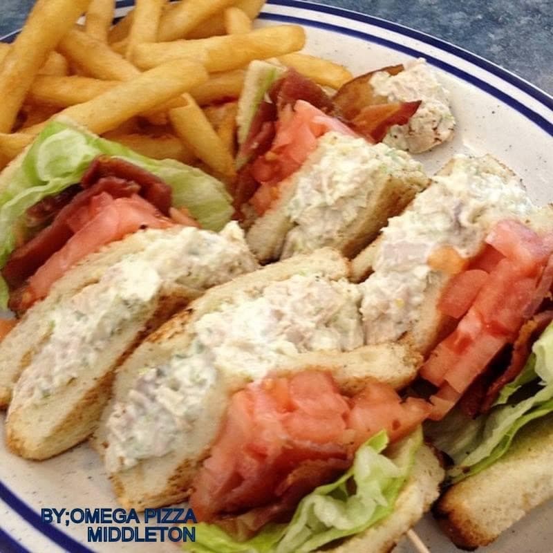 Tuna salad club sandwich with bacon, lettuce, and tomato served with golden french fries.