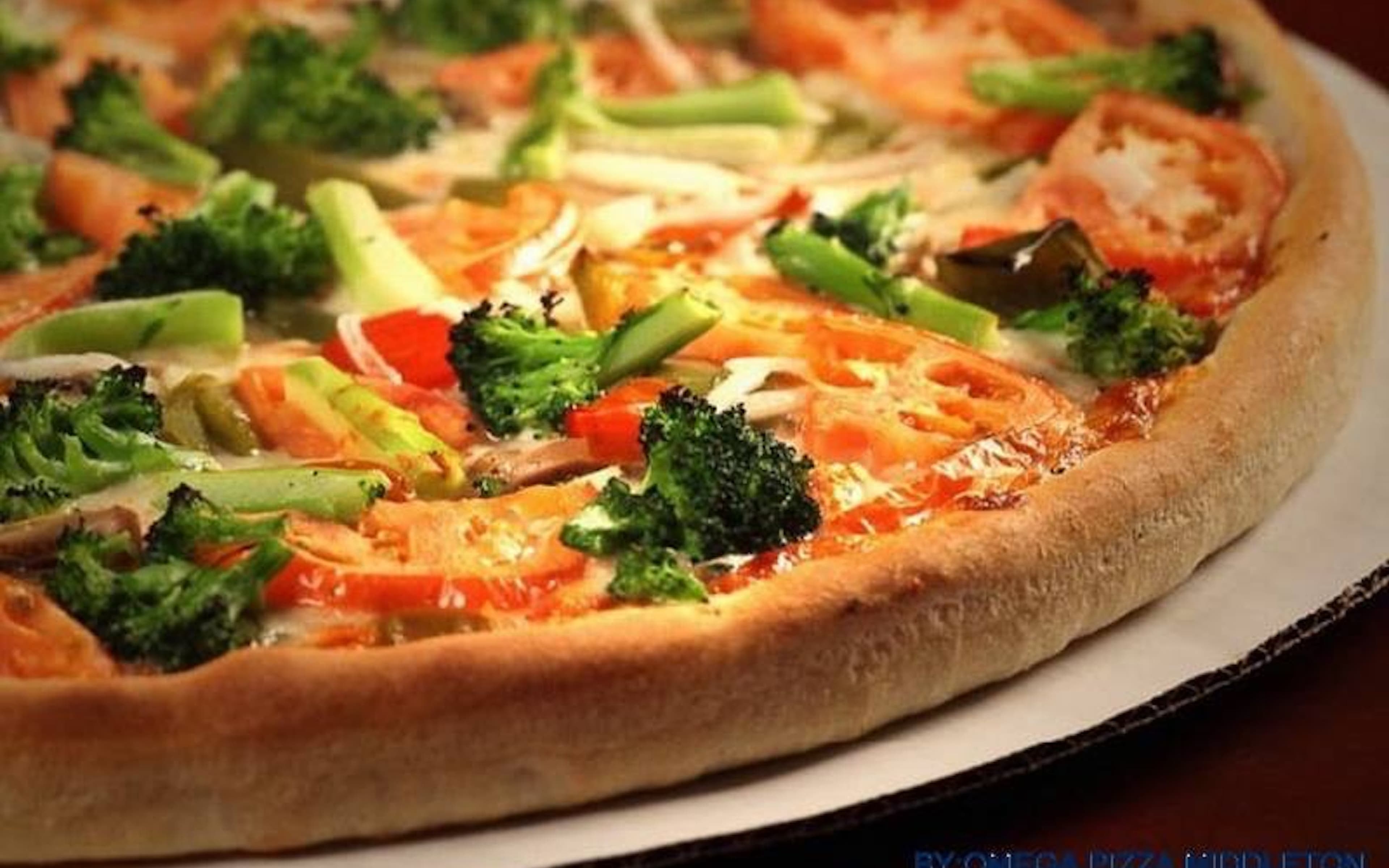 Thick-crust vegetable pizza topped with fresh broccoli florets, sliced tomatoes, and melted cheese.